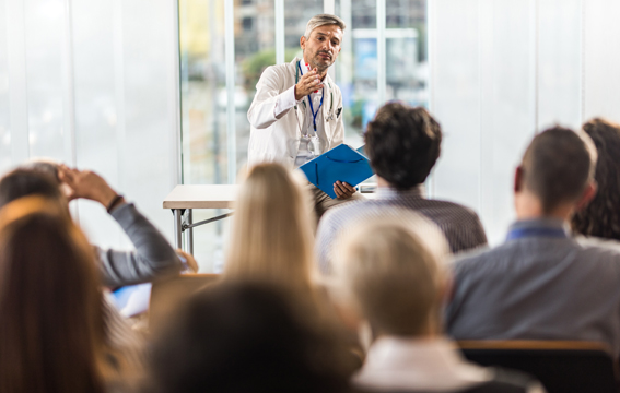 A doctor is presenting to an audience of medical device professionals at a conference. 